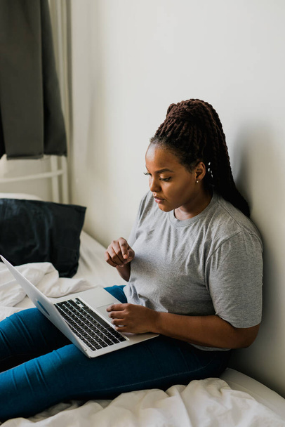 African american young woman using laptop on bed - technologies and communication and social network - Zdjęcie, obraz