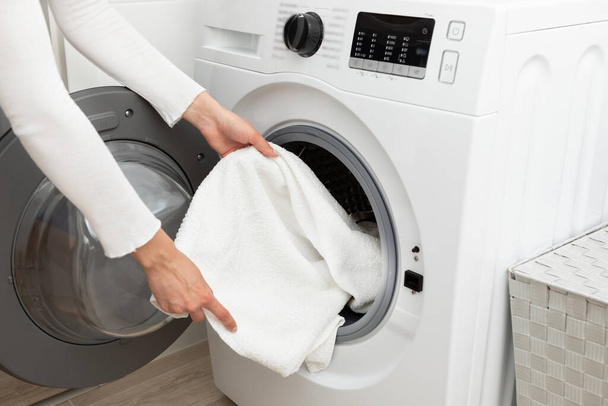 Γυναίκα αδειάζει το πλυντήριο σε λευκό φόντο. Υψηλής ποιότητας φωτογραφία - Φωτογραφία, εικόνα