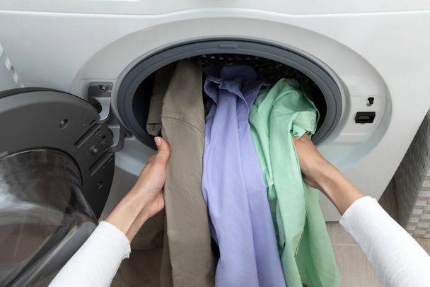 Kobieta wyjmująca kolorowe ubrania z pralki. Wysokiej jakości zdjęcie - Zdjęcie, obraz