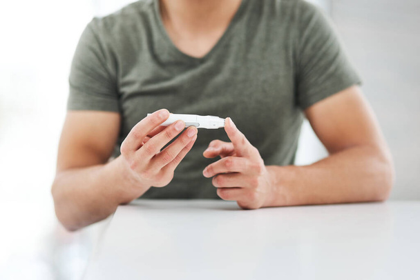 Ένα καθημερινό must για ένα διαβητικό. ένας αγνώριστος άντρας που χρησιμοποιεί εξέταση σακχάρου στο δάχτυλό του - Φωτογραφία, εικόνα