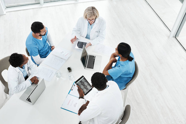 Να ενώσουν τις γνώσεις τους. Στιγμιότυπο υψηλής γωνίας ομάδας ιατρών που συναντιούνται σε αίθουσα συνεδριάσεων του νοσοκομείου - Φωτογραφία, εικόνα