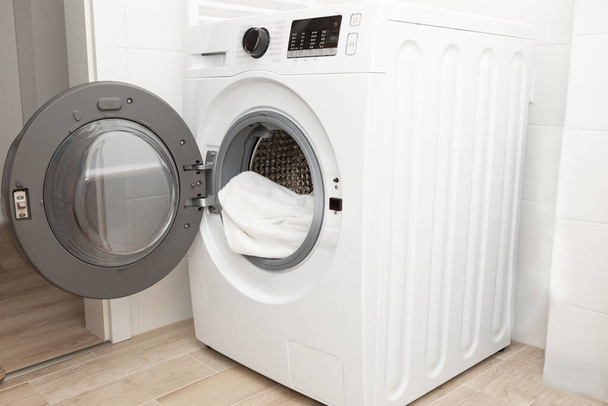 Çamaşır makinesindeki giysiler banyonun arka planında. Yüksek kalite fotoğraf - Fotoğraf, Görsel