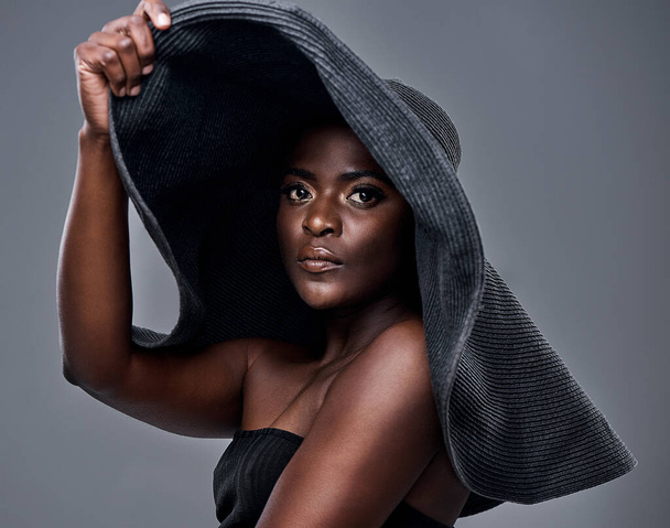 Wear the hat, its good for your skin. a young woman wearing a oversized sunhat against a grey background - Fotó, kép