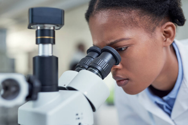 Shes noticed something...a young scientist using a microscope in a lab - Foto, imagen