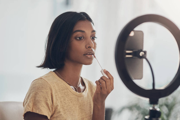 My go to gloss for that extra glam. a young woman applying makeup while filming a beauty tutorial at home - Photo, Image
