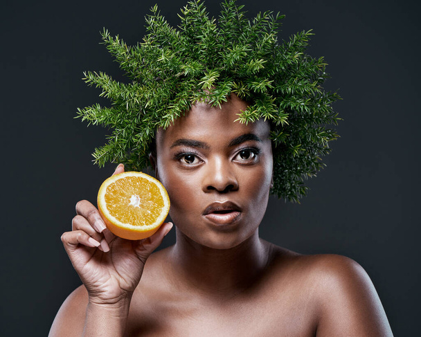 Oranges can do wonders for your skin. a beautiful woman holding an orange and wearing a leaf wreath on her head - Foto, Imagem