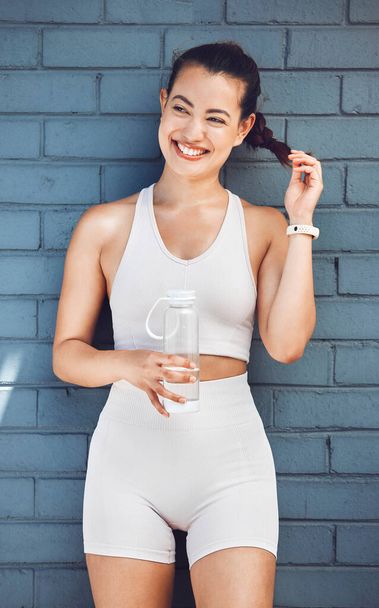 Fitness, exercise and water with a sports woman taking a drink during a break from her training workout. Health, cardio and hydration with a female athlete or runner thinking about her wellness. - Photo, Image
