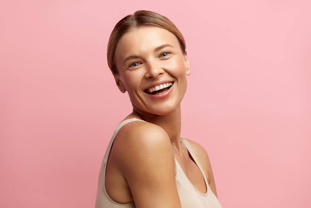 Beauty Woman Laughing Isolated Portrait. Blonde Woman Model With Smooth Skin Smiling Against Pink Background. Confident Female Enjoying Her Perfect Body After Cosmetology Treatment  - 写真・画像
