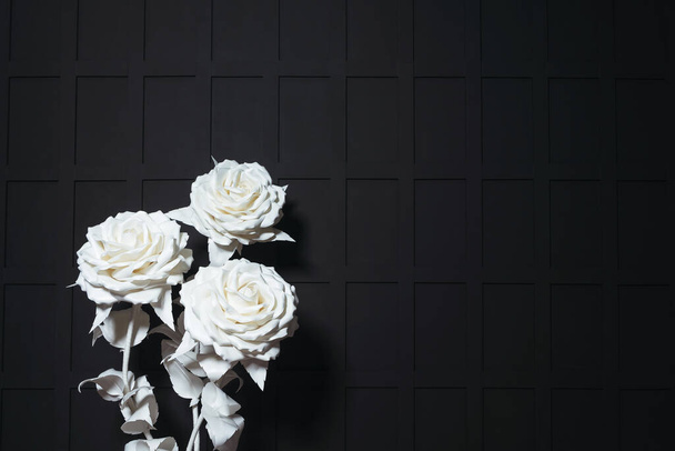 rosas artificiais gigantes brancas em um fundo preto. grandes flores de plástico no fundo de uma parede preta em um estúdio de fotografia. estilo gótico casamento foto zona - Foto, Imagem
