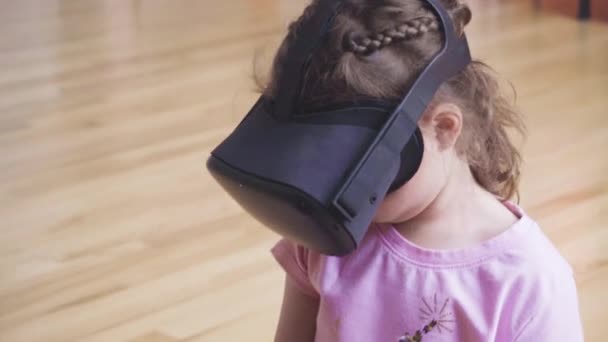 Mała dziewczynka gra w wirtualnej rzeczywistości w salonie, - Materiał filmowy, wideo