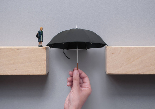 Hand holding umbrella bridging the gap between wooden blocks safe crossing - 写真・画像
