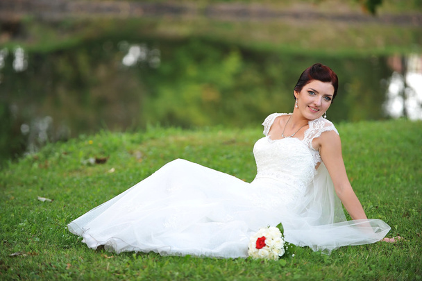 Bride sitting  on grass - Fotó, kép