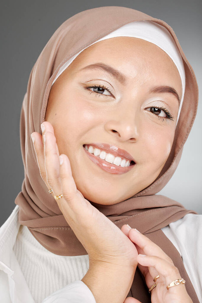 Muslim, beauty woman or arab model with smile for portrait, makeup or facial skincare in grey studio background. Skin, face or happy islamic girl with fashion, confident or headshot with brown hijab. - Photo, image