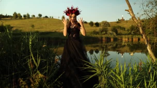 Schöne Frau Hexe im langen schwarzen Kleid Blumen Reifen, zaubern Sie einen Bann im Freien, Santa Muerte Karneval Halloween, Allerheiligen, Halloween gruselig Konzept, - Filmmaterial, Video