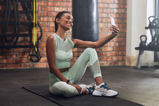 El sudor hace súper lindos selfies de gimnasio. una mujer joven tomando selfies durante un entrenamiento en el gimnasio - Foto, Imagen