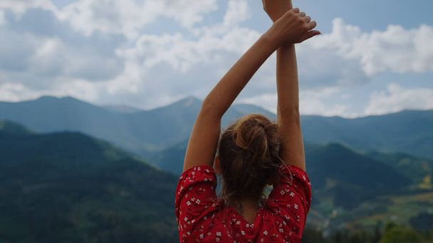 Unrecognizable girl raising hands watching beautiful gloomy mountains scenery close up. Back view of young woman resting on nature summer cloudy day. Unknown model enjoying tranquility at holiday. - Fotoğraf, Görsel