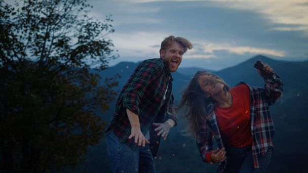 Cheerful family jump move hands outdoors on holiday evening sunset. Camping lovers express joy on mountains vacation. Active couple dance on nature close up. Traveling leisure fun activity concept. - Foto, Imagem