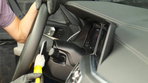 A professional worker cleaning a modern car, wiping the dashboard. Car dry cleaning - Foto, Imagen