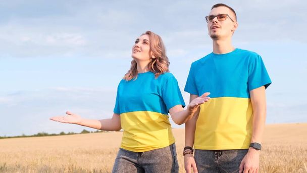 Ukrainan perhe on pukeutunut vaatteisiin lipun, sininen ja keltainen väri. Mies ja nainen laulavat keskellä vehnäpeltoa. Käsite sodan Ukrainassa - Valokuva, kuva