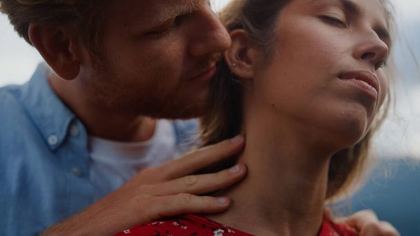 Closeup man hand stroking woman neck outside. Emotional redhead guy caressing beautiful girl at romantic date outdoor. Passionate couple spending honeymoon in mountains. Tenderness marriage concept - Photo, Image