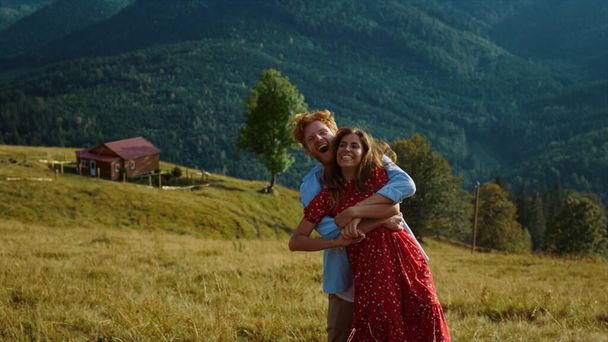 Young family dance together in summer mountains. Smiling couple have fun outside on sunny day. Laughing lovers embrace on holiday travel. Joyful husband wife relax on tourism activity. Love concept. - Φωτογραφία, εικόνα
