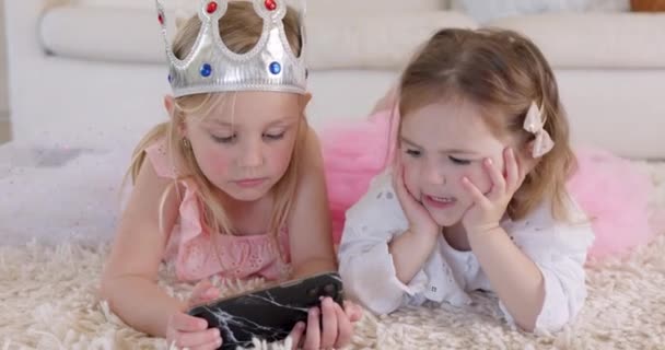 Βλέποντας βίντεο, τηλέφωνο και παιδιά σε ταινίες streaming στο διαδίκτυο. Χαριτωμένο, συγκόλληση και αδελφές μιλούν σε κοστούμι πριγκίπισσα χρησιμοποιώντας smartphone, internet και τεχνολογία για να παίξετε εκπαιδευτικά παιχνίδια στο σαλόνι. - Πλάνα, βίντεο