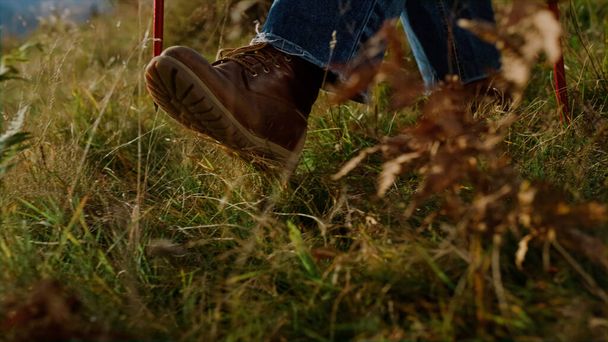 Closeup tourist shoes going mountains on hiking trail outdoors. Active man legs trekking autumn nature golden grass. Unknown traveler using ski poles on journey activity. Tourism vacation concept. - Photo, Image