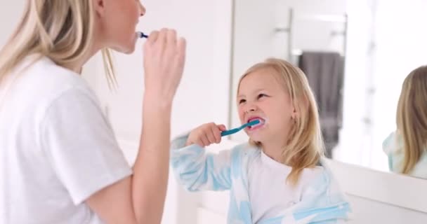 Zahnbürste, Mutter und Mädchen putzen ihre Zähne morgens im Badezimmer ihres Elternhauses. Glücklich, Bindung und Mutter machen eine Zahnhygiene-Routine für die Gesundheit mit oralen Produkten mit ihrem Kind - Filmmaterial, Video