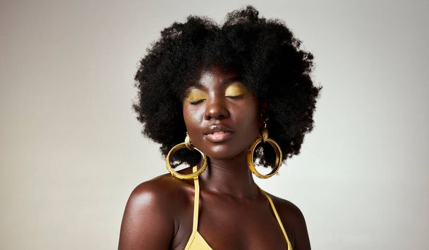 Black woman, face makeup and beauty eyes closed, thinking or fashion inspiration. African model, afro hair care and stylish, unique gold designer jewelry or cosmetics on gray mockup studio background. - Фото, зображення