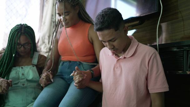 Latijns-Amerikaanse mensen bidden met de hand verbonden. Braziliaanse man en vrouw in gebed thuis woonkamer. Groep mensen aanbidden - Foto, afbeelding
