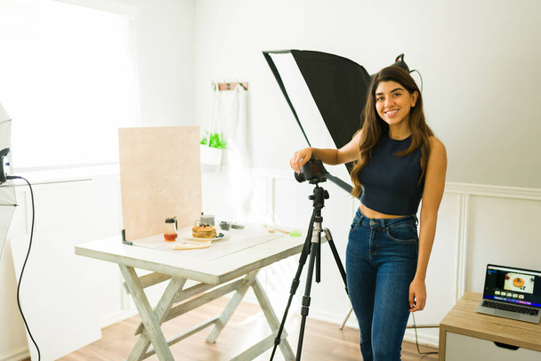 Piękna szczęśliwa kobieta fotograf uśmiechnięta podczas pracy robi profesjonalną sesję zdjęciową w studio - Zdjęcie, obraz
