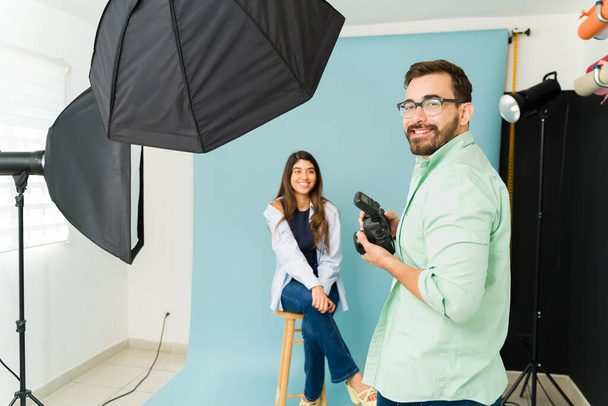 Iloinen valkoihoinen valokuvaaja hymyilee työskennellessään malli tekee valokuva ampua - Valokuva, kuva