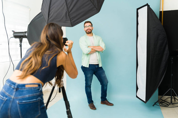 Vue arrière d'une photographe de sexe féminin prenant des photos d'un mannequin masculin posant lors d'une séance photo - Photo, image