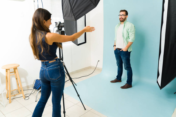 Vrouwelijke fotograaf in gesprek met een blanke man poedel positie tijdens een mode fotoshoot - Foto, afbeelding