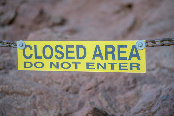 Phoenix, Arizona- Close-up of a yellow signage with Closed Area Do Not Enter at Camelback Mountain. Hanging yelow signage against the rock mountain wall background. - Photo, Image