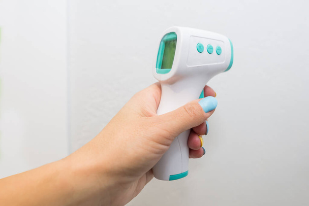 medición de temperatura sin contacto, sostiene la mano termómetro sin contacto aislado sobre fondo blanco
 - Foto, imagen