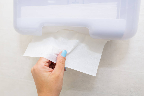 Dispensador de papel toalla. Mujer mano tomando toalla de papel - Foto, imagen