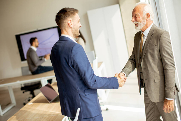 Senior business man handshaking with his young colleague in the office - Foto, Imagem