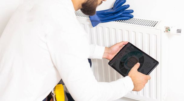 Opravit topný radiátor zblízka. muž opravuje chladič hasákem. Odstraňování vzduchu z chladiče. - Fotografie, Obrázek
