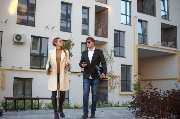 Meeting of business partners and negotiations between a young businesswoman and a manager on the background of a new residential apartment building - Foto, Imagem