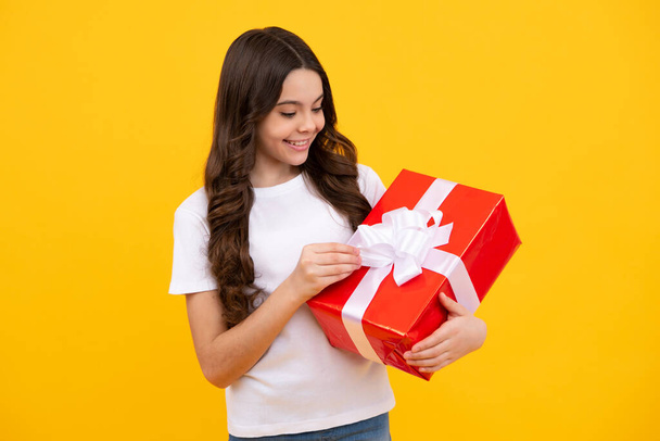 Emotional teenager child hold gift on birthday. Funny kid girl holding gift boxes celebrating happy New Year or Christmas. Happy teenager, positive and smiling emotions of teen girl - 写真・画像