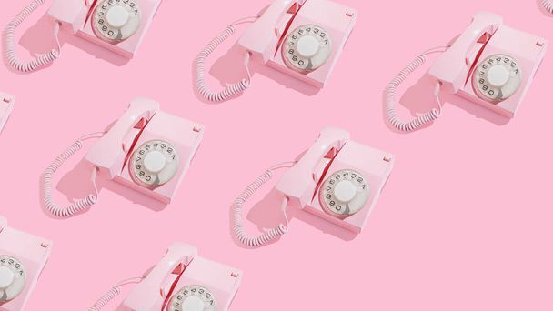 Trendy patroon gemaakt van oude roze wijzerplaat telefoons op heldere zonnige achtergrond met diagonale kopieerruimte. Retro communicatie concept. Vintage kantoor. - Foto, afbeelding