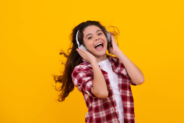 Amazed teenager. Young teen child listening music with headphones. Girl listening songs via wireless headphones. Wireless headset device accessory. Excited teen girl - Foto, Imagen