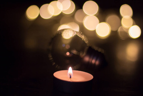 Kerze auf Glühbirnenhintergrund. Stromausfall in der Ukraine wegen Krieg - Foto, Bild