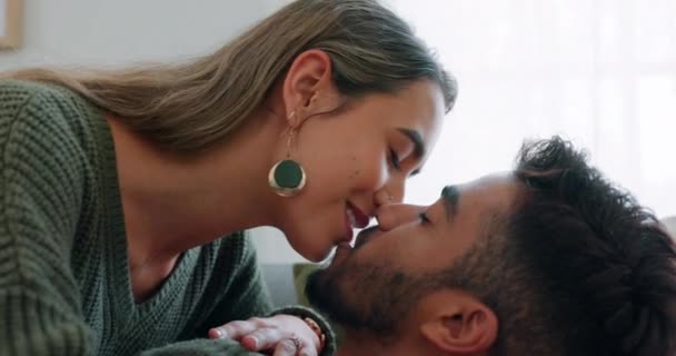 Couple, kiss or bonding on sofa in house living room or relax home in love, trust or security. Smile, happy and bonding interracial man or woman in intimate, romantic or support union on lounge couch. - Footage, Video