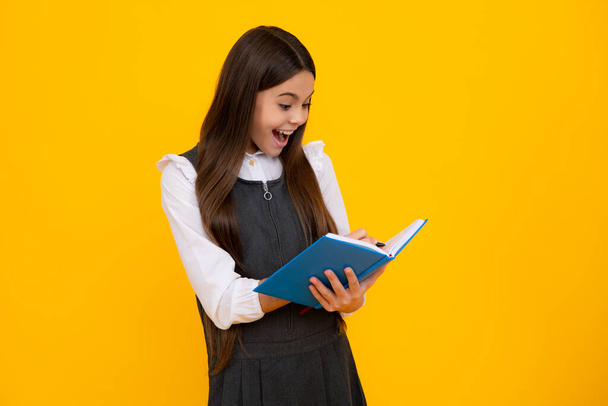 Amazed teen girl. Back to school. Teenager schoolgirl with book ready to learn. School girl children on isolated yellow studio background. Excited expression, cheerful and glad - Zdjęcie, obraz