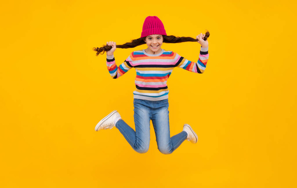 School girl in winter clothes and warm hat. Winter holiday vacation. Child fashion model. Jump and run. Happy teenager, positive and smiling emotions of teen girl - Photo, Image