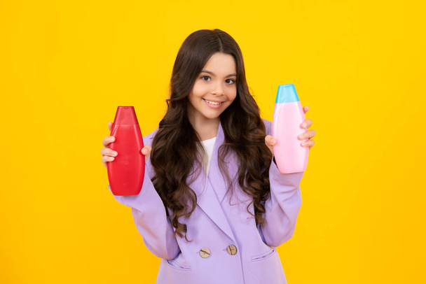 Teenage girl with shampoos conditioners or shower gel. Kids hair care cosmetic product, shampoo bottle. Happy teenager, positive and smiling emotions of teen girl - Photo, image