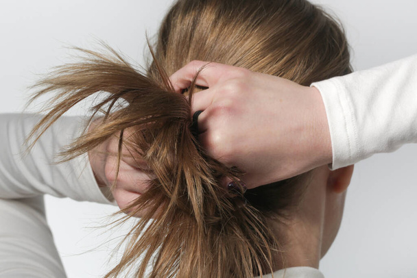 Serie foto 's van het maken van een lage paardenstaart met elementaire elastische haarband. Achteraanzicht van jonge vrouw gebonden haar haar in paardenstaart. - Foto, afbeelding