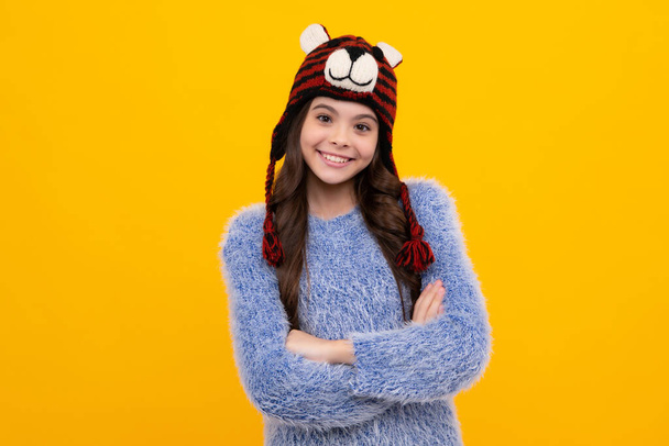 Beautiful winter kids portrait. Teenager girl posing with winter sweater and knit hat on yellow background. Happy teenager, positive and smiling emotions of teen girl - Foto, afbeelding